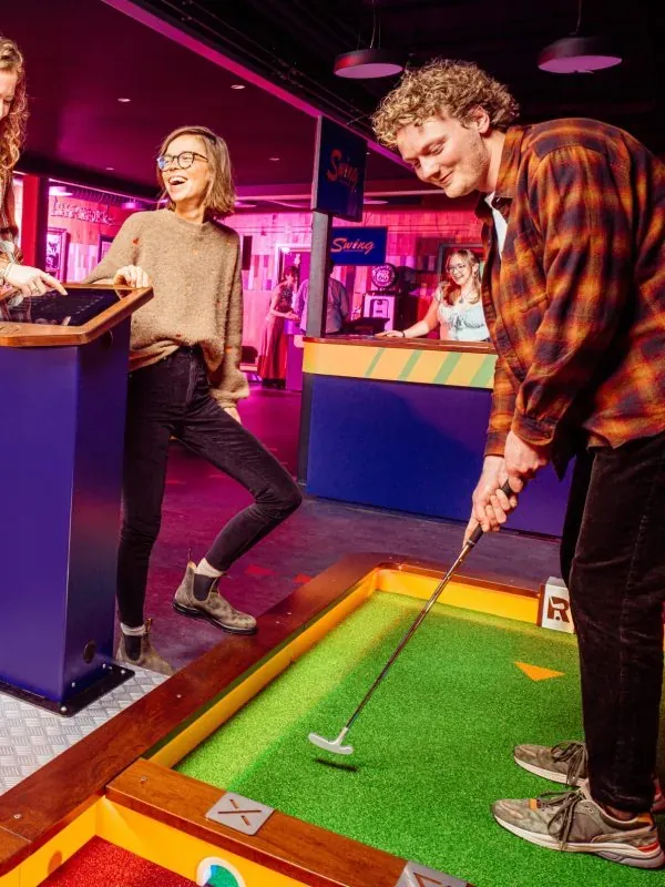Un joueur prépare son putt pendant que son amie s’amuse