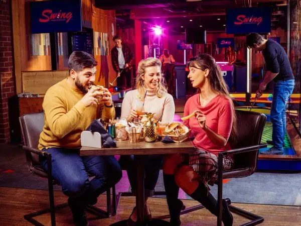 Des amis partagent des burgers chez Swing, mini-golf interactif à Genève